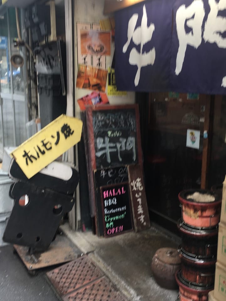 The noren and the pavement blackboard at the Shibuya original, reading HALAL BBQ Restaurant at Gyumon Shibuya