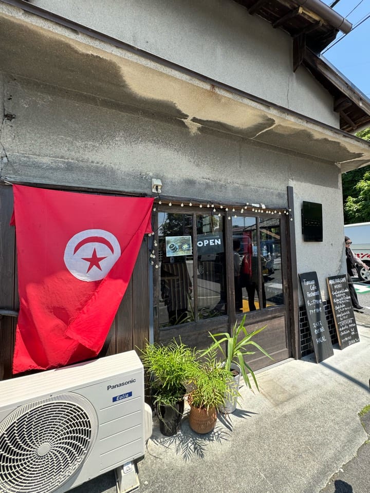 The shop front on a machiya building, with a Tunisian flag and a chalkboard listing halal dishes at sahha halal restaurant, Horen-cho