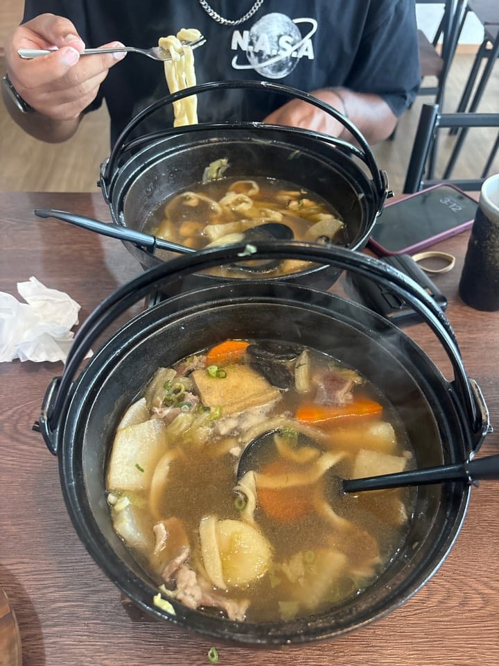 Two iron pots of hot broth with flat noodles, daikon, carrot and sliced meat at T&T Fujiyama Halal Restaurant, Fujiyoshida